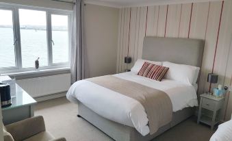 a large bed with white linens and a striped blanket is in a room with a window at Ferry House Inn