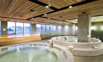 a modern , well - lit indoor space with wooden ceiling and large windows , containing a spa area featuring multiple hot tubs at The Riverside Hotel
