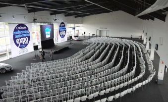 a large conference room with rows of white chairs arranged in a semicircle , ready for an event at Hilton Garden Inn Silverstone