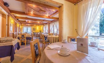 a restaurant with wooden tables and chairs , a teapot on the table , and framed pictures on the wall at Hotel Lo Scoiattolo