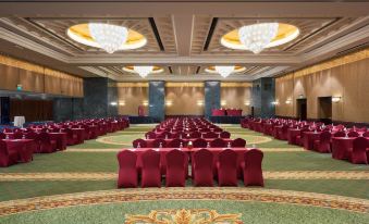 a large , empty conference room with rows of red chairs and chandeliers hanging from the ceiling at Grand Nile Tower