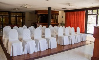 a large , empty room with rows of white chairs set up for an event or meeting at Camino Real Tikal‎