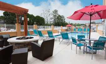 an outdoor patio with a pool surrounded by lounge chairs and umbrellas , providing a relaxing atmosphere at TownePlace Suites Gainesville Northwest