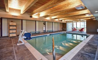 a large indoor swimming pool with a wooden ceiling and red chairs around the edge at Home2 Suites by Hilton Mechanicsburg