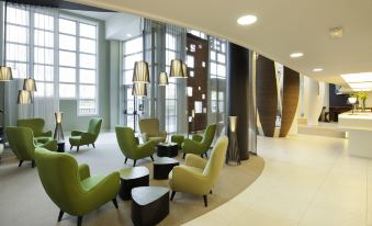 a modern office space with green and yellow chairs arranged in a circle around a coffee table at Novotel Paris 14 Porte d'Orleans
