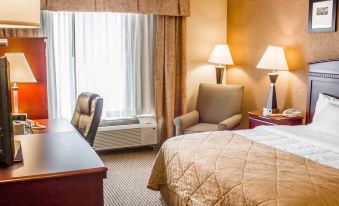 a hotel room with a large bed , two chairs , and a window , all lit by lamps at Hotel Veranda DuBois