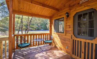 a wooden cabin with a large window , outdoor furniture , and a view of trees outside at Wilderness Presidential Resort