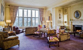 a luxurious living room with ornate furniture , large windows , and a purple carpet , providing a sense of grandeur at Bovey Castle