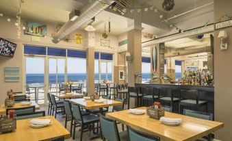 a restaurant with wooden tables and chairs , a bar area , and a view of the ocean at Nantasket Beach Resort