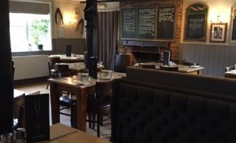 a restaurant with wooden tables and chairs , a fireplace , and blackboards on the wall at Kings Head