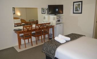 a modern hotel room with a bed , dining table , chairs , tv , dining table , and mirror at Best Western Caboolture Gateway Motel