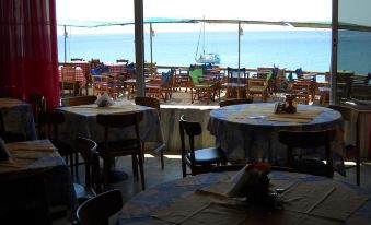 a restaurant with tables and chairs , all set up for dining , overlooks the ocean and has a view of the beach at Argo Spa Hotel