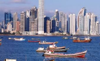 a city skyline with many boats in the water and colorful boats in the foreground at Hotel Principe