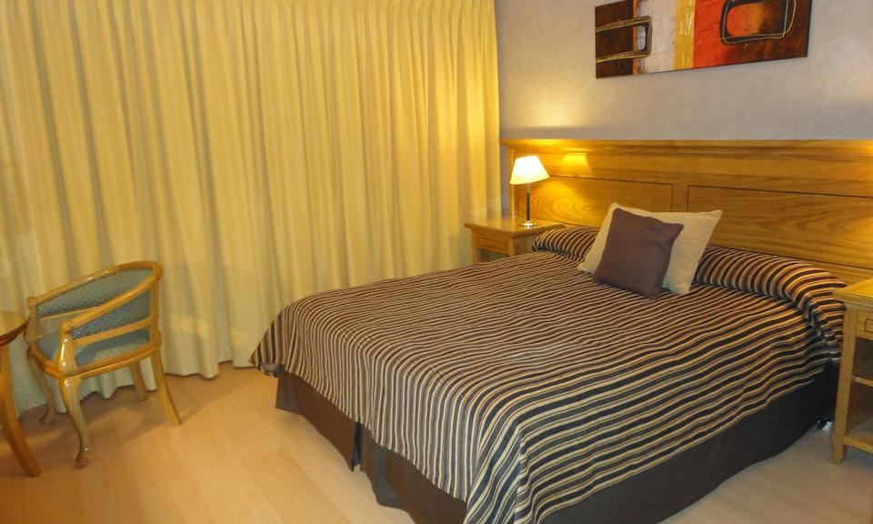 a hotel room with a bed , curtains , and lamps , giving it a cozy and inviting atmosphere at Hotel Presidente