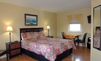 a large bedroom with a wooden floor , a king - sized bed , and a dining table in the room at The Clipper Inn