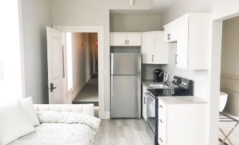 a small , clean kitchen with a refrigerator , oven , and microwave , as well as a couch in the room at Inn on Central