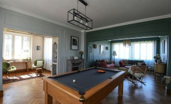a pool table is set up in a living room with chairs and a fireplace at Entre Terre et Mer