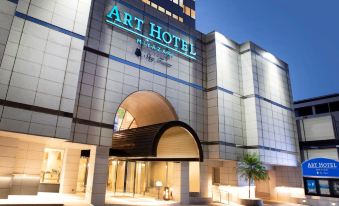 "a modern hotel entrance with the name "" art hotel "" displayed above it , and palm trees lining the entrance" at Art Hotel Miyazaki Sky Tower