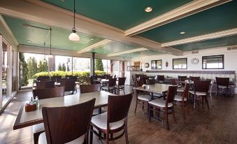 a large , empty restaurant with wooden tables and chairs , a green ceiling , and potted plants at Best Western Edgewater Resort