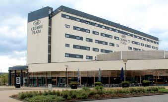 a large , modern hotel building with a brown facade and several umbrellas in front of it at Crowne Plaza Reading East
