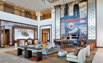 a large , modern living room with a couch and chairs in front of a large painting on the wall at Renaissance Chicago Glenview Suites Hotel