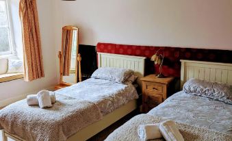 a cozy bedroom with two beds , each topped with towels , and a window in the background at Bartholomew Arms