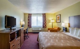 a hotel room with a bed , desk , and television , as well as a television and other furniture at Quality Inn