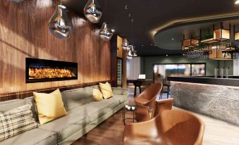 a modern lounge area with a long couch , several chairs , and a fireplace in the background at Mercure HAN Sur Lesse