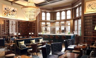 a modern library with large windows , wooden bookshelves , and comfortable seating areas , under a hanging light fixture at De Vere Tortworth Court