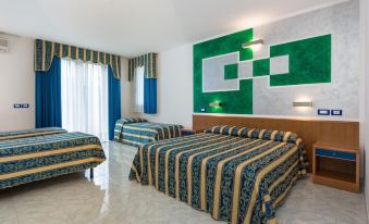 a hotel room with two beds , a green and blue striped comforter on one bed , and a blue and white striped curtain at Hotel Centrale