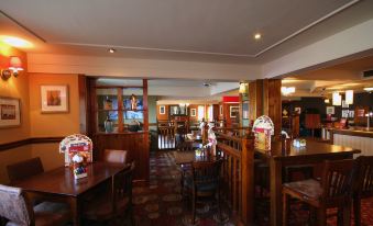 a dining room with wooden tables and chairs , along with a variety of paintings on the wall at Premier Inn Blackpool Airport