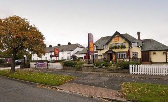 a street view of a building with a large front door and a white picket fence at Premier Inn Wirral (Greasby)