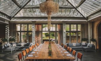a long wooden table with chairs is set up in a room with large windows at Hampton Manor
