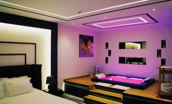 a modern bedroom with a purple neon light , white bed , and black nightstands on either side of the bed at Hotel Delta