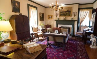 a cozy living room with antique furniture , including a piano , couch , and chairs , as well as a fireplace at Inn at Mitchell House