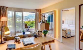 a modern hotel room with a large window , wooden desk , and living area with comfortable seating at Suitenhotel Parco Paradiso