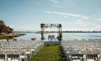a wedding ceremony is taking place on a grassy field near a body of water , with chairs set up for guests at The Inn at Longshore