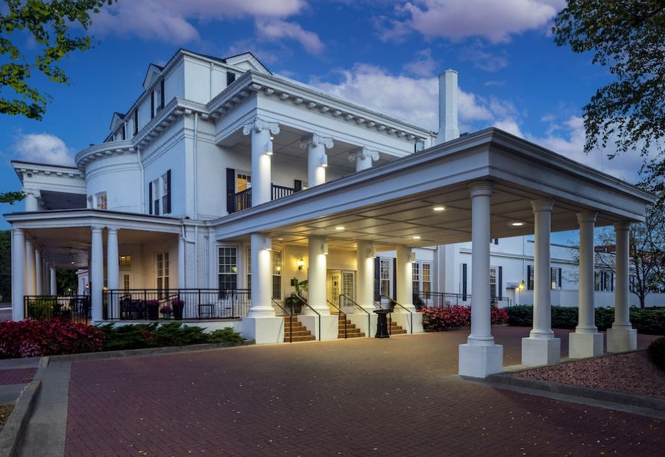 a large white building with columns and a porch is lit up at night , overlooking a street at Historic Boone Tavern