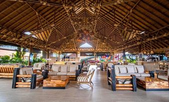 a large indoor area with a thatched roof , white walls , and wooden furniture , under the shade of hanging lights at Hotel Campestre las Camelias