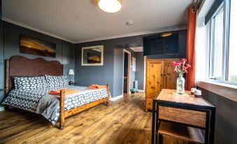 a cozy bedroom with hardwood floors , a wooden bed , and a television mounted on the wall at Burnside Cottage