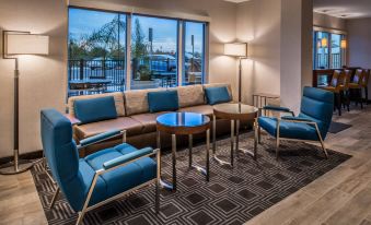 a modern living room with blue chairs and a couch arranged around a coffee table at TownePlace Suites Merced