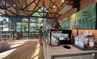 a coffee shop with a wooden floor and a high ceiling , featuring a dining table with various cups and food items at The O Valley Hotel