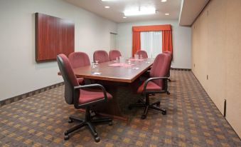 a conference room with a large wooden table surrounded by chairs , and a painting on the wall at Home2 Suites by Hilton Ogden