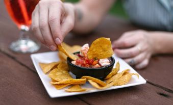 a person is dipping a tortilla chip into a bowl of salsa on a white plate at Bocawina Rainforest Resort