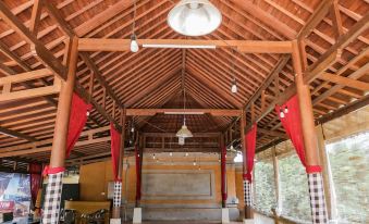 a wooden building with a sloping roof , red curtains hanging from the ceiling , and an open space under it at Ubud Hotel & Cottages