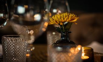 a vase with a yellow flower in it is placed on a table surrounded by wine glasses at The Fox