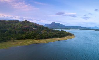 a serene lake surrounded by lush greenery , with a small island in the middle of the water at Heritance Kandalama