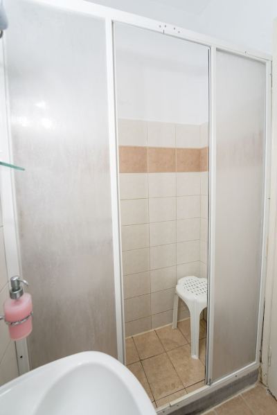 a bathroom with two glass shower doors , a white shelf , and a pink toilet , reflecting the cleanliness and comfort of the bathroom at Hotel Summery