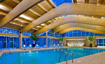 a large indoor swimming pool surrounded by lounge chairs , where people are relaxing and enjoying their time at Crowne Plaza Lombard Downers Grove