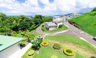 a beautiful view of a green park with trees , flowers , and a house in the background at Siesta Hotel